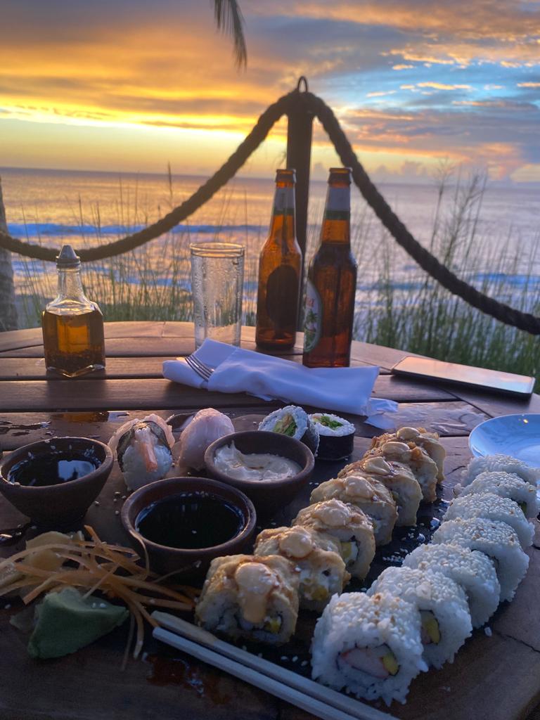 Sushi platter and drinks on a beachfront table at sunset in Rancho Santana, Tola, Nicaragua.