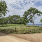 A stunning view of Rancho Santana Prime Corner lot showcasing lush greenery, and expansive views of the ocean.