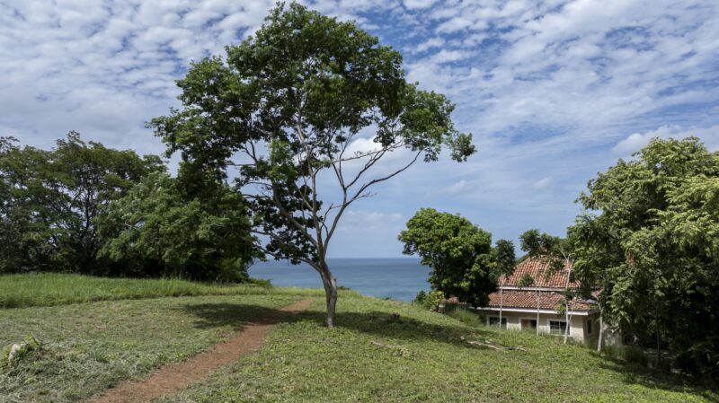 A stunning view of Rancho Santana Prime Corner lot showcasing lush greenery, and expansive views of the ocean.