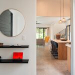 Entry hallway with round mirror and floating shelves looking toward the kitchen and living area in Rancho Santana.