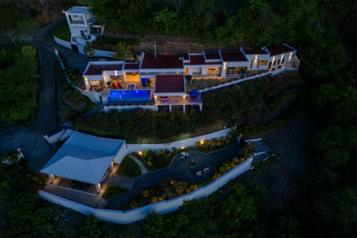 Twilight aerial of the Pacific Marlin Estate with its infinity pool glowing above the bay