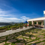 Stone-paved terrace with a covered outdoor lounge and bay views