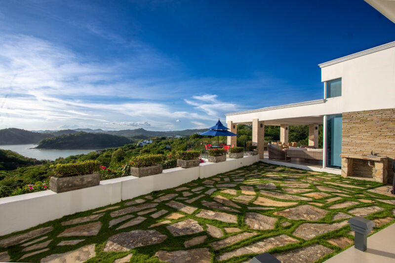 Stone-paved terrace with a covered outdoor lounge and bay views