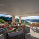 Covered terrace lounge with colorful cushions overlooking the water