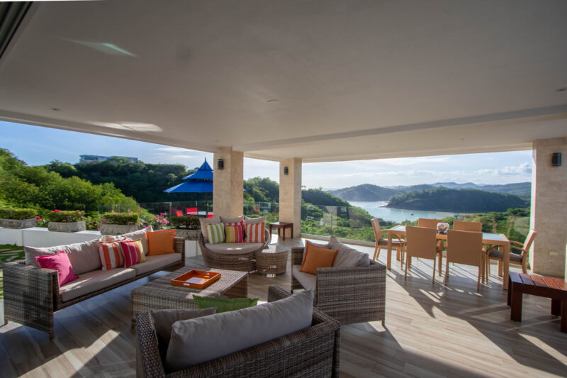 Covered terrace lounge with colorful cushions overlooking the water