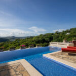 Pool deck with sun loungers above San Juan del Sur Bay