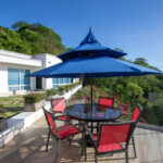 Terrace dining set under a blue umbrella with a view of the bay