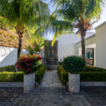 Landscaped front entrance with palms and a stone walkway
