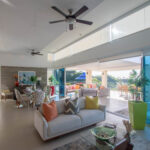 Glass-walled living and dining space opening to the ocean