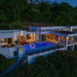 The Pacific Marlin Estate at dusk with lit interiors and a glowing pool