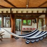 Living area with a hammock and walls of glass to the jungle