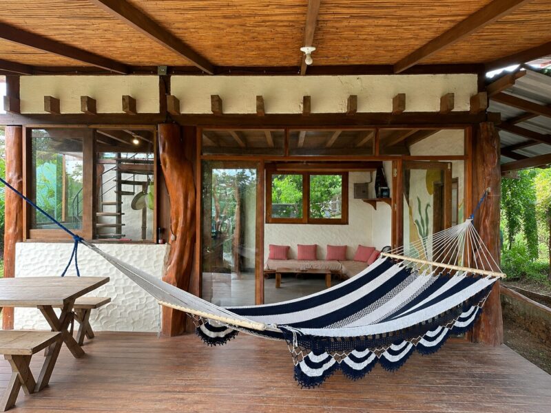 Living area with a hammock and walls of glass to the jungle