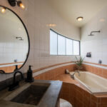 Bathroom with a round mirror and built-in tub