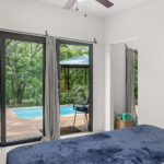 Bedroom with sliding glass doors opening to the deck and pool