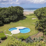 Clover-shaped resort pool and gardens with the beach beyond