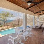 Covered porch with a private pool, loungers, and ocean view