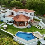 Bay-view home in Pacific Marlin — aerial of the red-roof villa, pool, and lawn