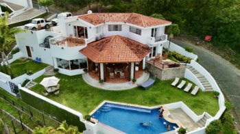 Bay-view home in Pacific Marlin — aerial of the red-roof villa, pool, and lawn