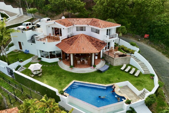 Bay-view home in Pacific Marlin — aerial of the red-roof villa, pool, and lawn