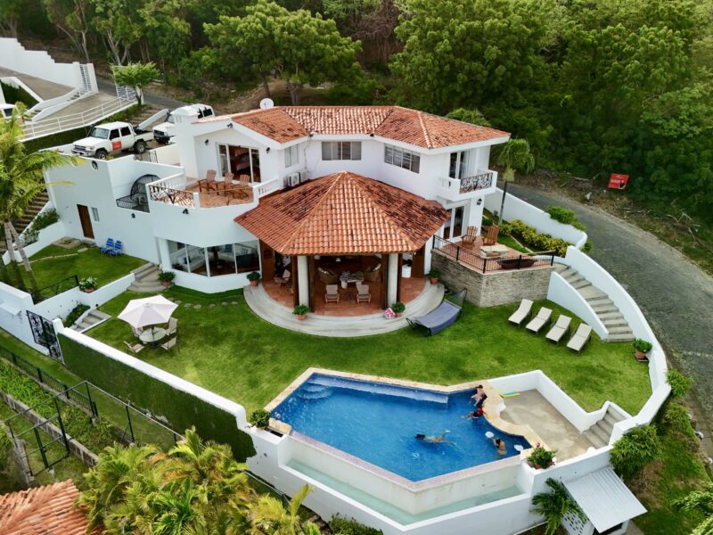 Bay-view home in Pacific Marlin — aerial of the red-roof villa, pool, and lawn