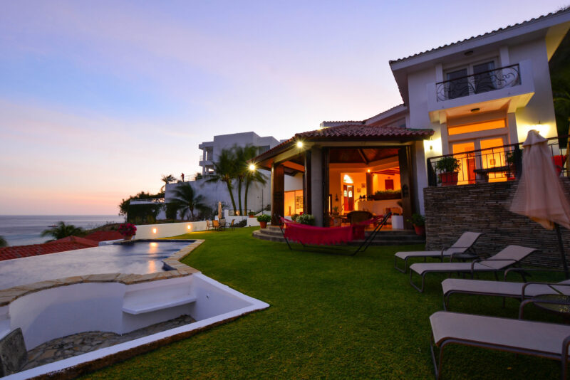 Hillside villa lit at dusk above the bay