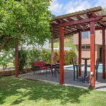Pool and pergola beside the grass backyard
