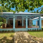 Blue clapboard home with a covered porch and gardens
