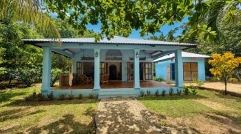 Blue clapboard home with a covered porch and gardens