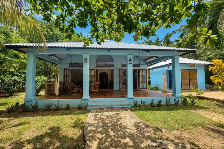 Blue clapboard home with a covered porch and gardens