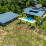 Aerial view of the home, pool, and surrounding acreage