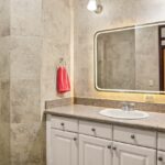 Bathroom with stone tile and lit vanity mirror