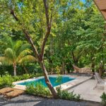 Pool deck with lounge chairs and garden at Hacienda Iguana pool home