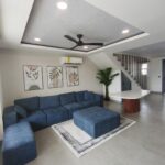 Living room with sectional sofa, ceiling fan, and stairway